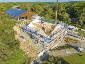 Bird's eye view of a construction site in a natural environment with solar building nearby, timber