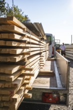 Wood planks on a transport vehicle in sunlight, prepared for construction, timber house
