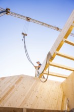 Timber structure under construction with a crane and a blue sky in the background, timber house
