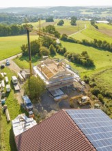 Large construction site with crane in the middle of a green landscape with solar panels on