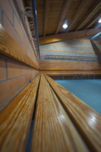 Long wooden bench on a brick wall with ceiling lights, Schlehengäu Sporthalle Gechingen, Calw