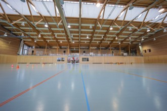 Empty sports hall with floor lines, wooden structure and several basketball hoops, Schlehengäu