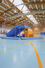 Gymnastic equipment and mats in the wooden sports hall, bright and spacious atmosphere, Schlehengäu
