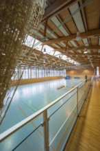 Interior view of a sports hall with marked fields and a dominating wooden structure, Schlehengäu