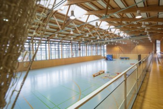 View of a spacious sports hall with basketball hoop and marked playing fields on the ground,