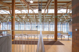 Spacious interior of a sports hall with wooden beams and large windows that let in lots of light,