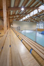 Grandstand area of a gymnasium with wooden benches and modern architecture, Schlehengäu sports hall