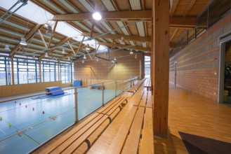 Interior view of a gym with wooden benches and large windows, Schlehengäu Sporthalle Gechingen,