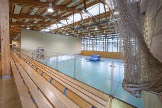 View over the stand of a sports hall with wooden structure and playing field, Schlehengäu