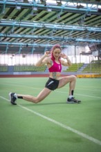Woman stretching on green field, demonstrating flexibility and athletic energy, middle distance