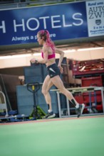 Female athlete dynamically running sideways through the interior of a hall, middle distance runner