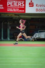 Female athlete sprints quickly through a hall, the movements are dynamic, middle distance runner