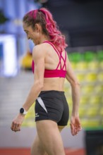 Back view of a woman with pink hair and sporty clothes, looks relaxed and satisfied, middle