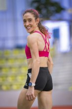 Woman in sporty clothes turns around and smiles, satisfied and relaxed, middle distance runner