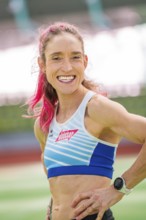 Woman smiling friendly with a wristwatch on in the stadium, middle distance runner Katharina