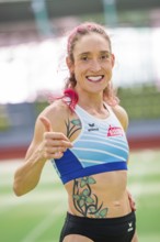 Woman showing thumbs up and smiling with tattoos in stadium, middle distance runner Katharina