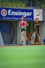 Female athlete running past a banner in a hall, middle distance runner Katharina Jaiser,
