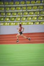 Female athlete running at high speed in an indoor sports hall, middle distance runner Katharina