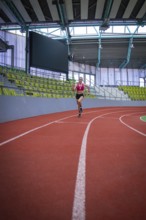 Woman running on a red indoor track in a stadium, middle distance runner Katharina Jaiser,