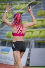 Sportswoman raises her arms while running on a track in a hall, middle distance runner Katharina