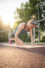 Woman doing yoga exercises on a mat in sunlight, showing concentration and commitment, middle