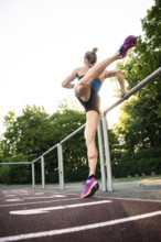 Dynamic pose of a woman stepping high on a running track in a sporting environment, middle distance