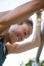 Woman practicing outdoors, smiling hard under sunlight during training, middle distance runner