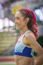 Happy sportswoman with pink hair in the stadium. Smiles and looks satisfied, middle distance runner