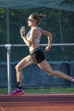 Female athlete moving on a running track, wearing sunglasses and athletic clothing, showing