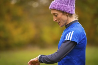 Woman wearing blue sportswear wearing purple cap in autumn setting, middle distance runner