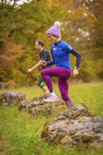 Training of men and woman over rocks in a colorful autumn environment, middle distance runner