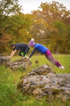 Two people training over rocks in an autumnal landscape, middle distance runner Katharina Jaiser,