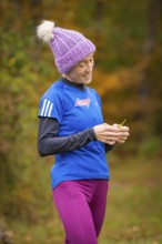 Woman wearing purple cap standing in autumn and looking at something, middle distance runner