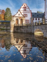 Kochberg Castle in autumn with bridge and reflection, colorful leaves in the castle moat,