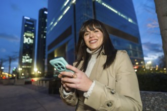 Young professional woman smiling while using her smartphone for networking and social media in a