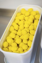 Many yellow balls in a plastic container, presented industrially, chocolate quail eggs, Easter
