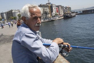 Istanbul, Turkey. June 23rd 2025. An old Turkish man fishing on the Galata Bridge near Karikoy