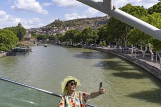 Tbilisi, Georgia. July 7th 2025. An Asian tourist poses for a photograph on the Bridge of Peace
