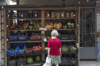 Tbilisi, Georgia. July 29th 2025. A woman shopping at a local grocery shop selling fruit and