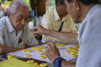 Bangkok, Thailand. March 4th 2025. Old men play Chinese board games on a Sunday morning in Lumphini