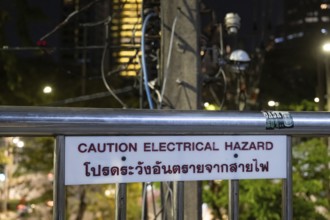 Bangkok, Thailand. March 4th 2025. A Caution Electrical Hazard sign near an electricity pylon with