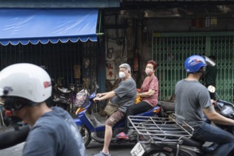 Bangkok, Thailand. March 18th 2025. An elderly couple wearing masks on a motor scooter in the busy
