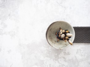 Paint brushes with bamboo handles are bundled together in a ceramic bowl, resting on a white table