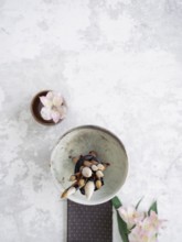 Calligraphy brushes tied together in a bowl on a textured background with pink flowers and a