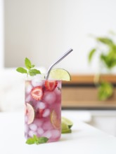 Strawberry mojito mocktail, full of ice, lime, mint, and drinking with a metal straw