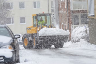 Loader clearing snow from snow-covered cars on streets in Ystad, Skåne County, Sweden, Scandinavia