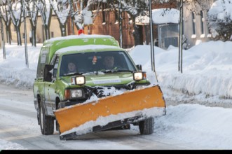 Small truck with mounted snow plow clearing snow on streets in Ystad, Skåne County, Sweden,