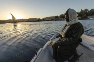 Aswan, Egypt. January 11th 2013 Local Nubian man fishing in the Nile with a Felucca sail boat at