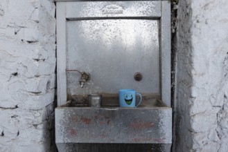Aswan, Egypt. December 9th 2022 Cean water drinking fountain with plastic smiley face mug, along