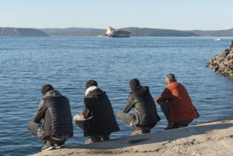 Canakkale, Turkey. February 18th 2022 Turkish men squatting beside the Dardanelles Straight